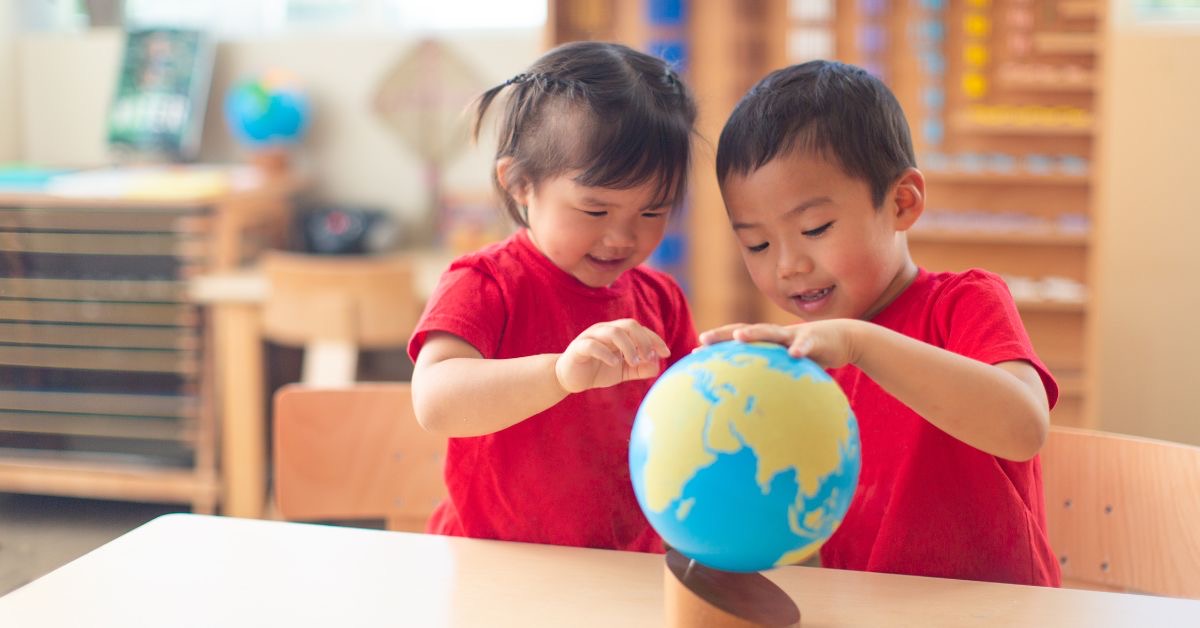 A boy and girl in red t-shirts, look at a globe.